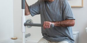 Man using the SuperPole to help him off the toilet
